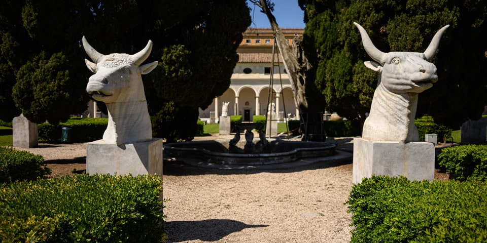 Two colossal ancient marble bull heads flanking the fountain in the Great Cloister of the Baths of Diocletian, Rome