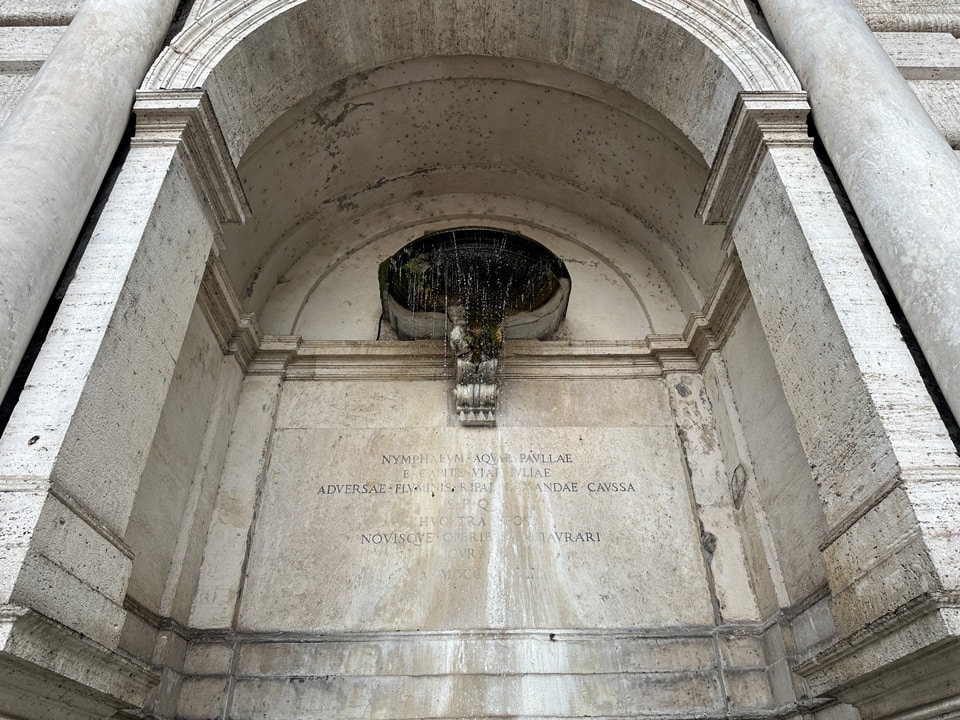 Latin inscription recording the 19th-century transfer of the Acqua Paola nymphaeum to Piazza Trilussa, Rome